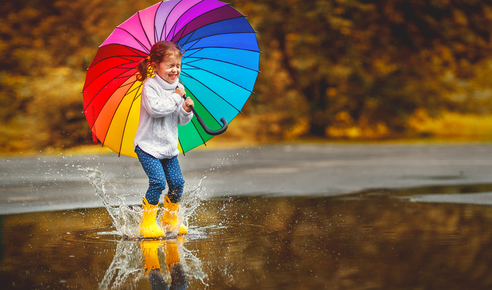가을비에 우산을 들고 놀고 있는 작은 여자아이